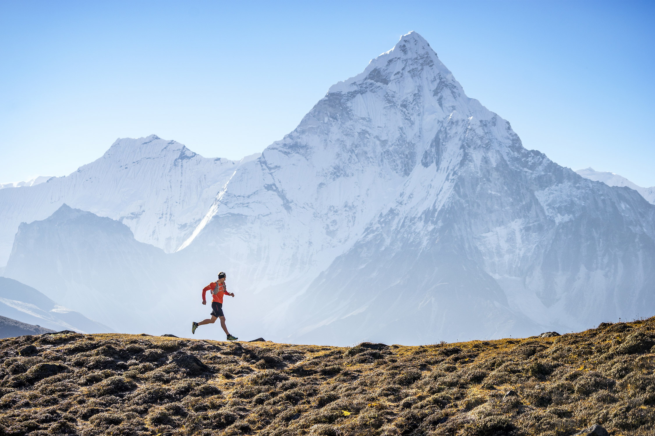 Ueli Steck trail running in the Khumbu Valley of the Nepal Himalaya, with Ama Dablam in the background, during his acclimating process for a climbing expedition. Ueli stayed in Dzonghla where he would run trails, run Lobuche Peak, and climb Cholatse before his primary objective, Nuptse.